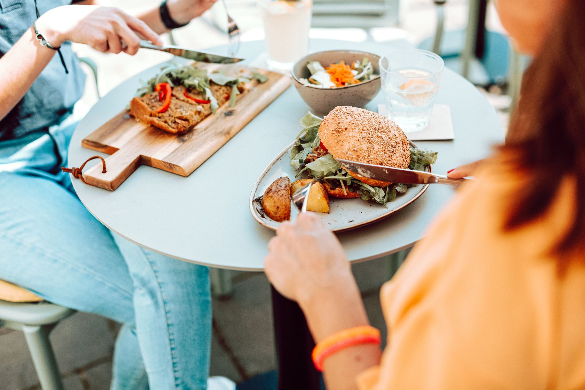 Zwei Personen essen Burger und Salat an einem Tisch im Café