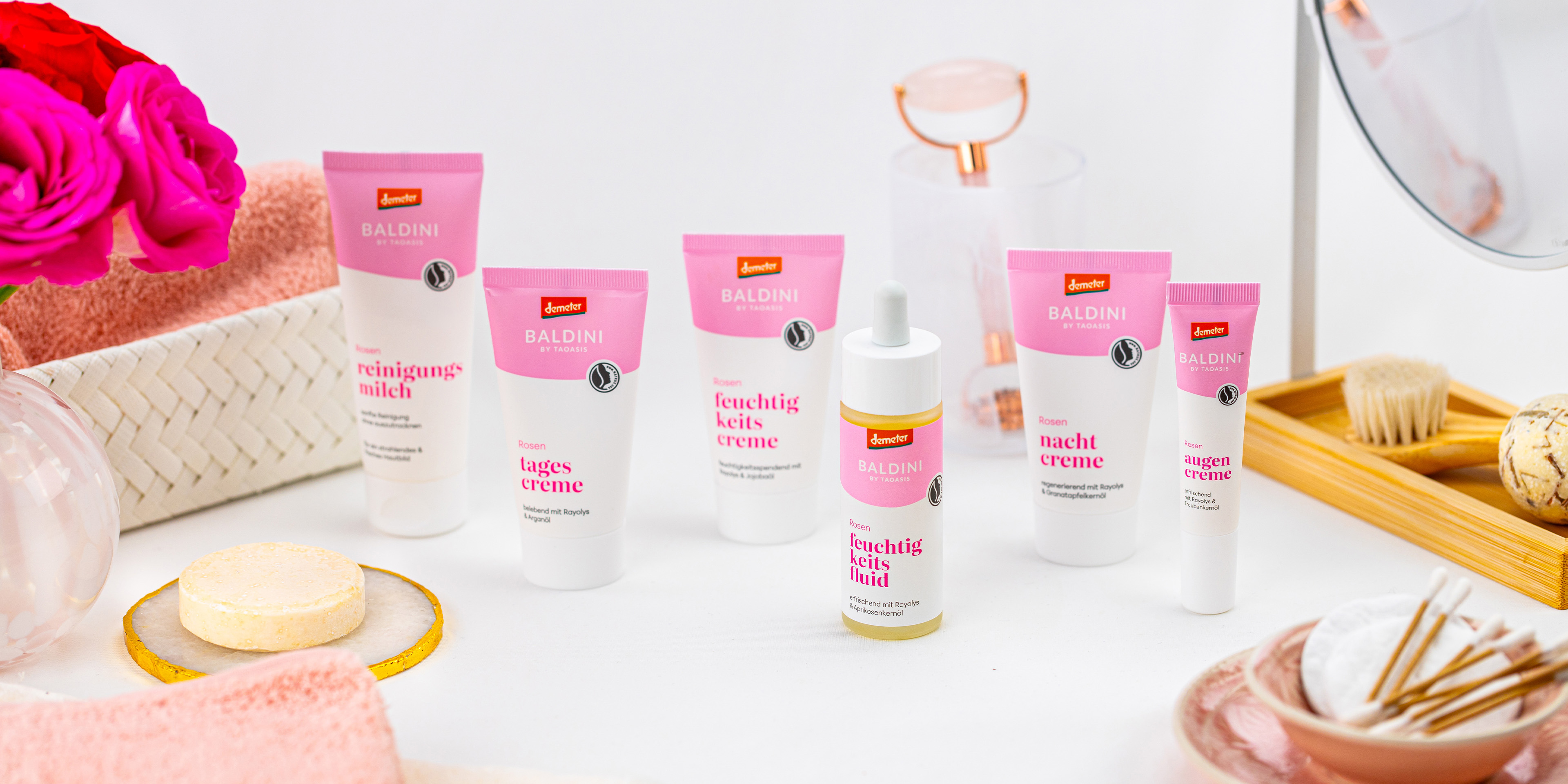 Baldini Rosen-Gesichtspflege für anspruchsvolle Haut mit Reinigungsmilch, Tagescreme, Feuchtigkeitscreme, Feuchtigkeitsfluid, Nachtcreme und Augencreme, dekoriert mit Rosen und Pflegeaccessoires.