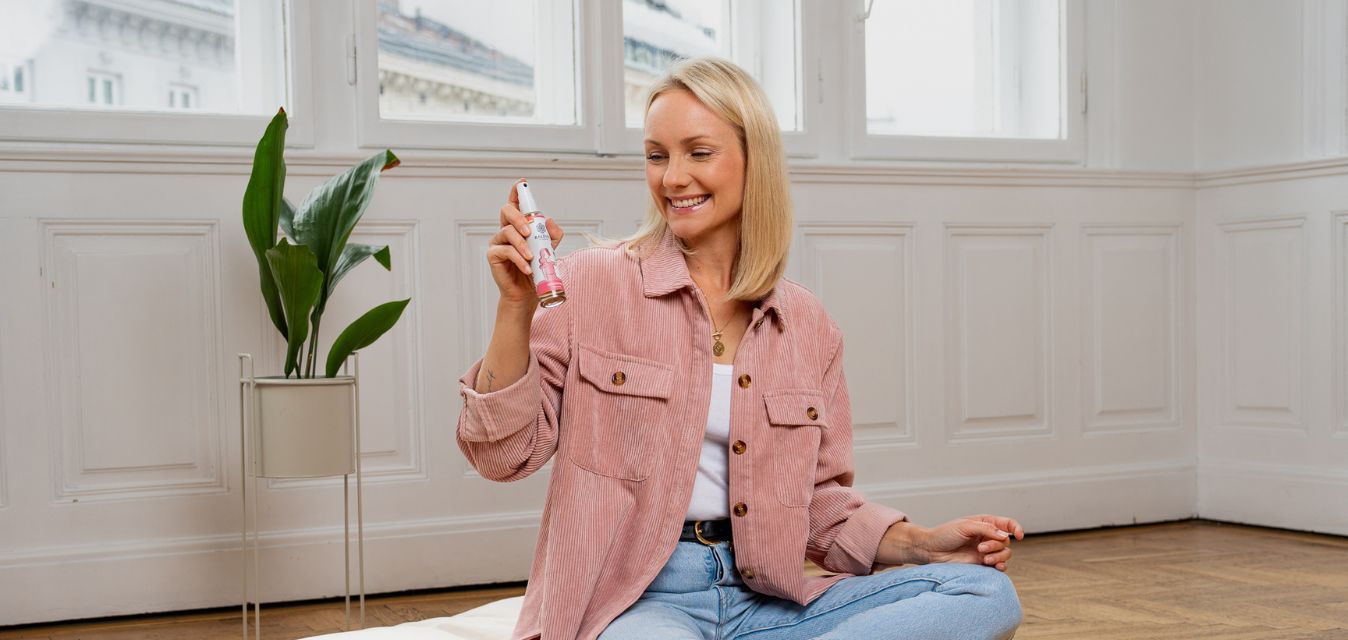 Sitzende Frau mit Raumspray in der Hand