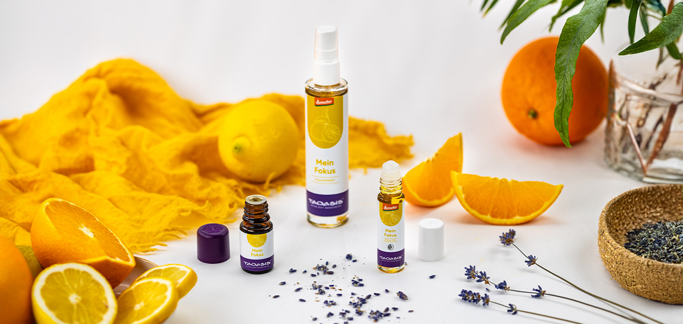 TAOASIS „Mein Fokus“-Produkte umgeben von Orangen, Zitronen und Lavendel auf hellem Hintergrund.