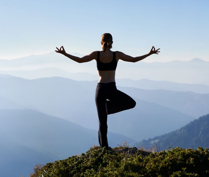 Frau macht Yoga auf einem Berg.
