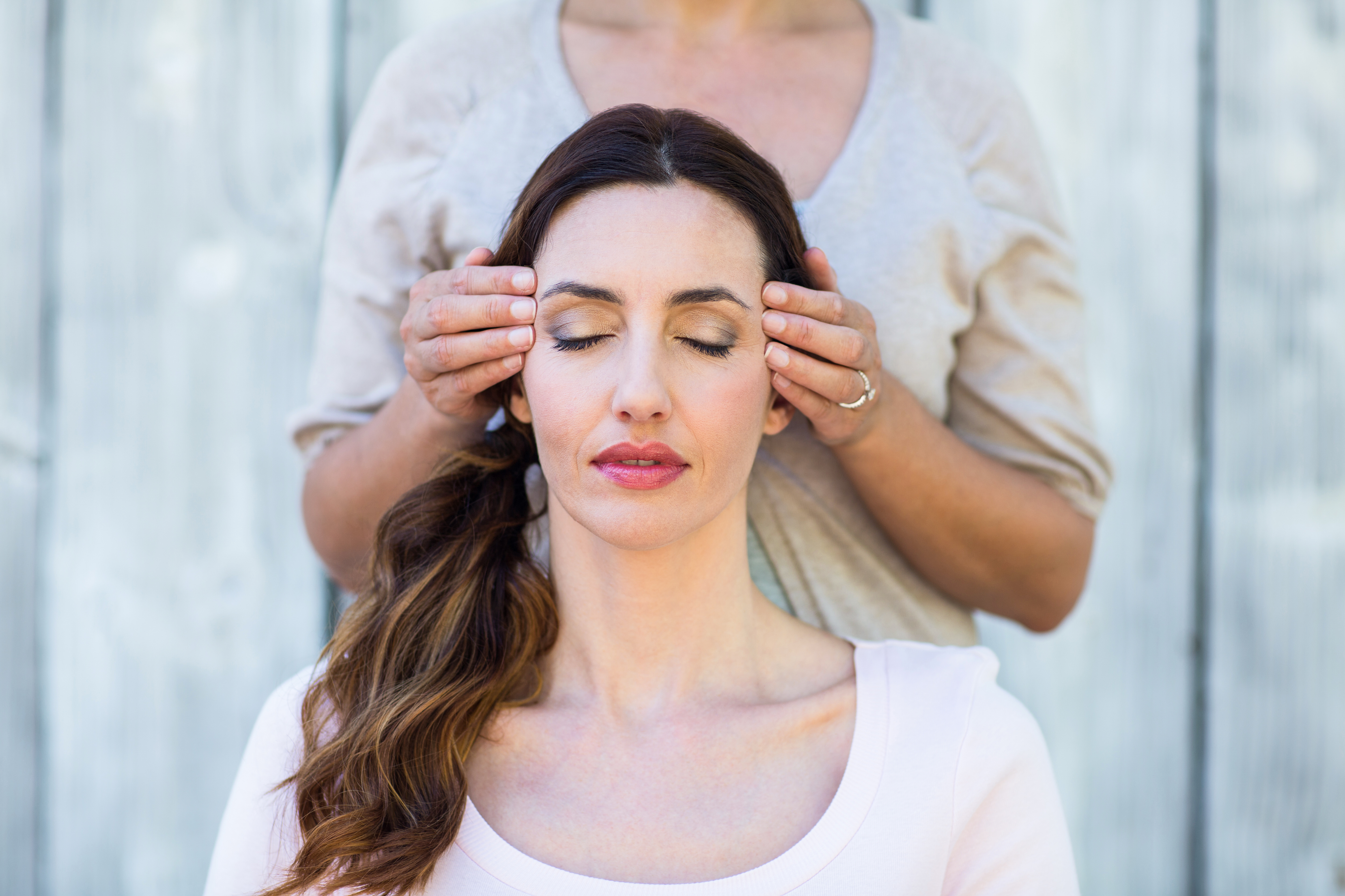 Frau bekommt Reiki Massage im Gesicht