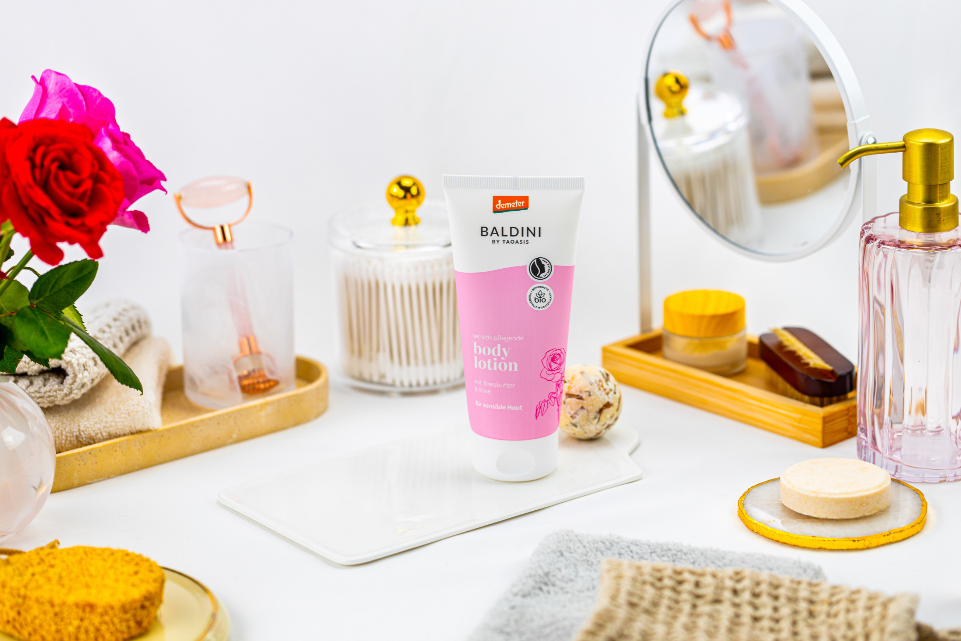 Bodylotion Rose von Baldini und Badumgebung. Mit Spiegel, Blumen, Seife, Schwamm, Handtüchern.