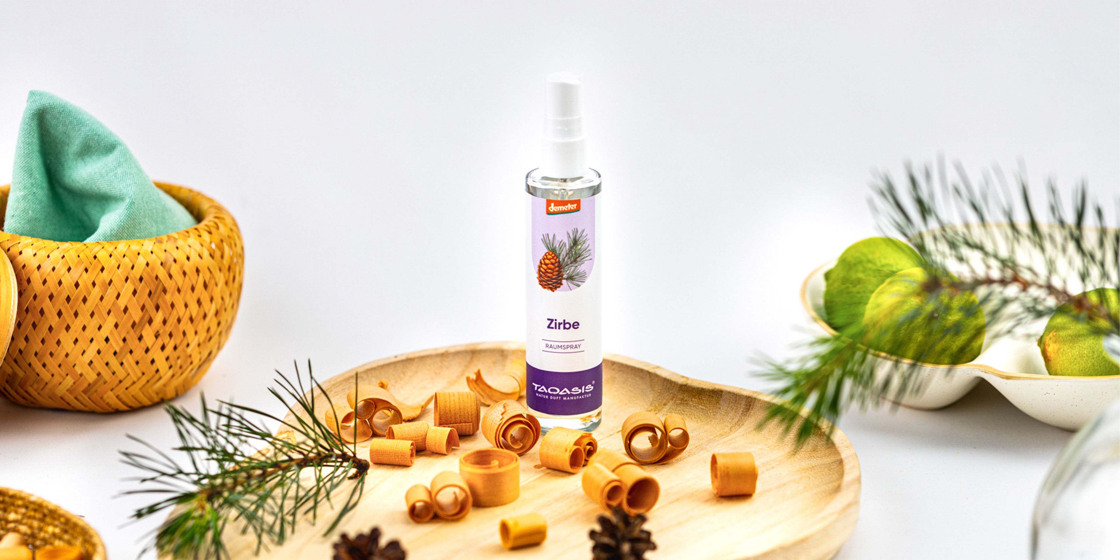 TAOASIS Zirbe Raumspray auf einem Holzteller, dekoriert mit Zirbenholzspänen, Kiefernzweigen und natürlichen Wohnaccessoires.