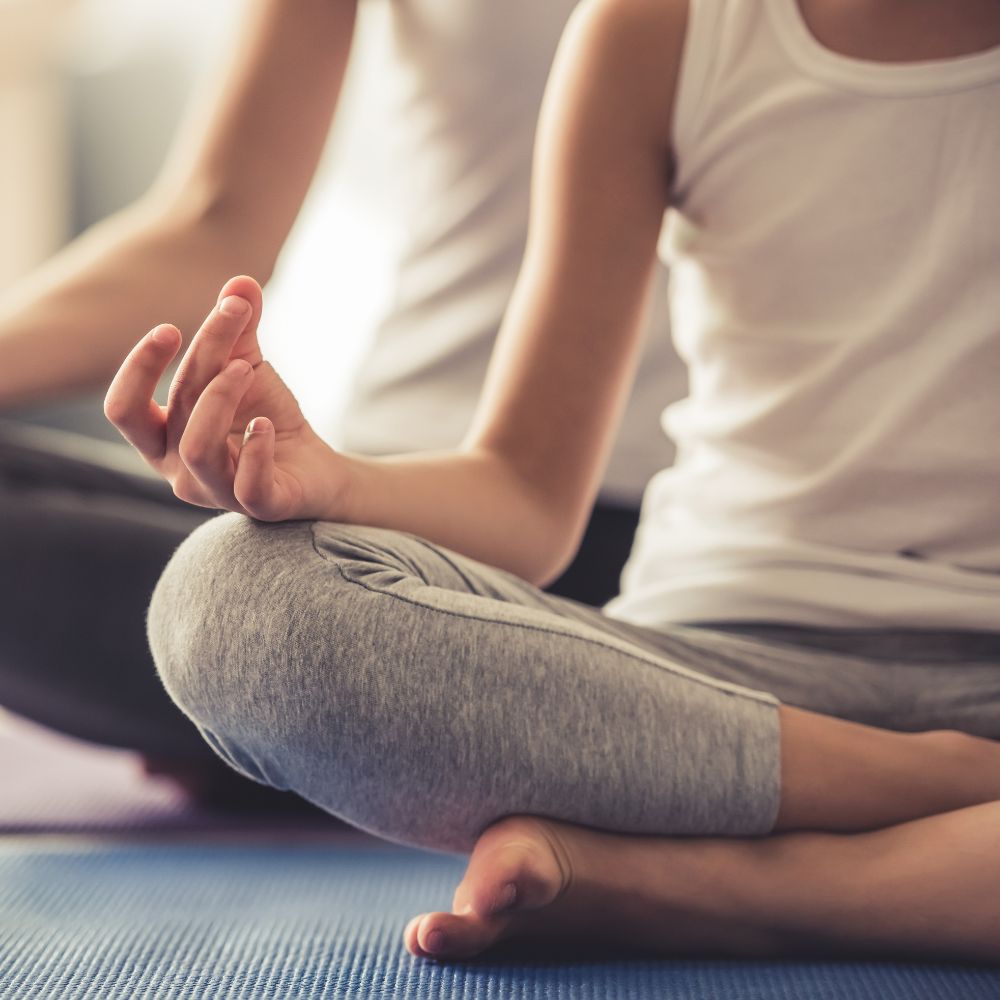zwei Frauen im Schneidersitz auf einer Yogamatte