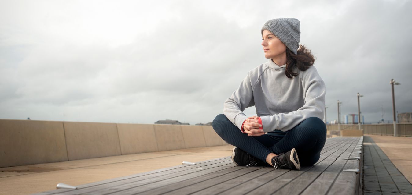 Frau sitzt auf einer Bank und schaut in die Ferne