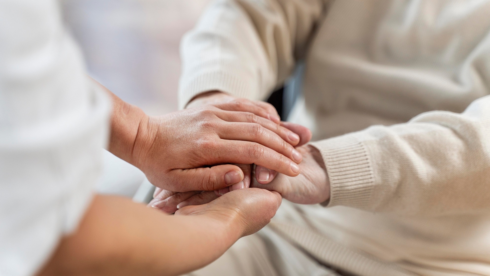 Zwei Hände halten unterstützend die Hand einer älteren Person – Zeichen von Fürsorge und Nähe.