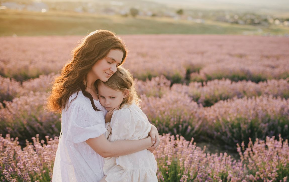 Frau umarmt Kind vor einem Lavendelfeld