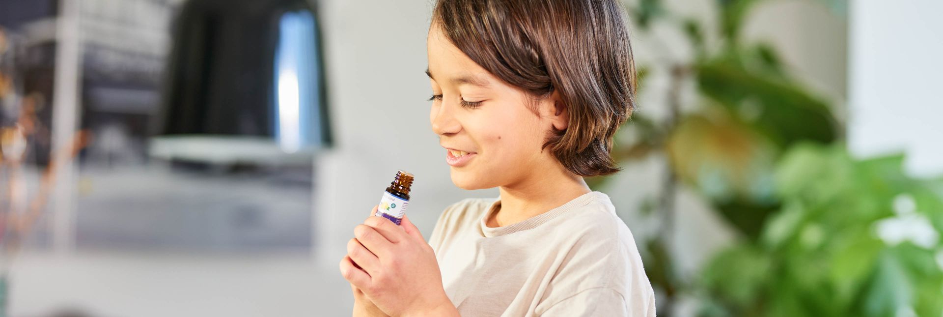 Kind riecht an einem Fläschchen mit ätherischem Öl