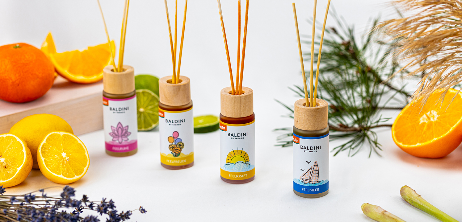 Vier Baldini Raumduft-Diffuser mit Duftstäbchen, umgeben von Zitrusfrüchten und Pflanzen.