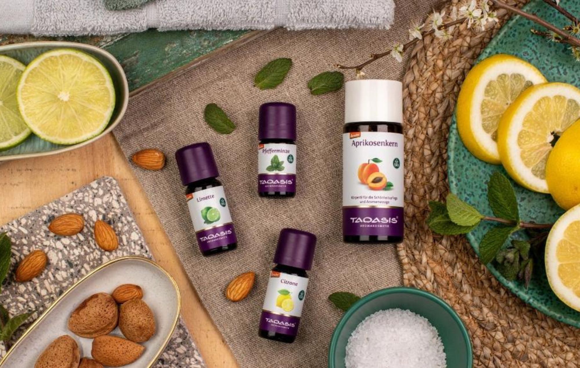 Sommerliches Peeling mit ätherischen Ölen, Aprikosenkernöl, Zitrusfrüchten, Minze und Mandeln dekorativ arrangiert