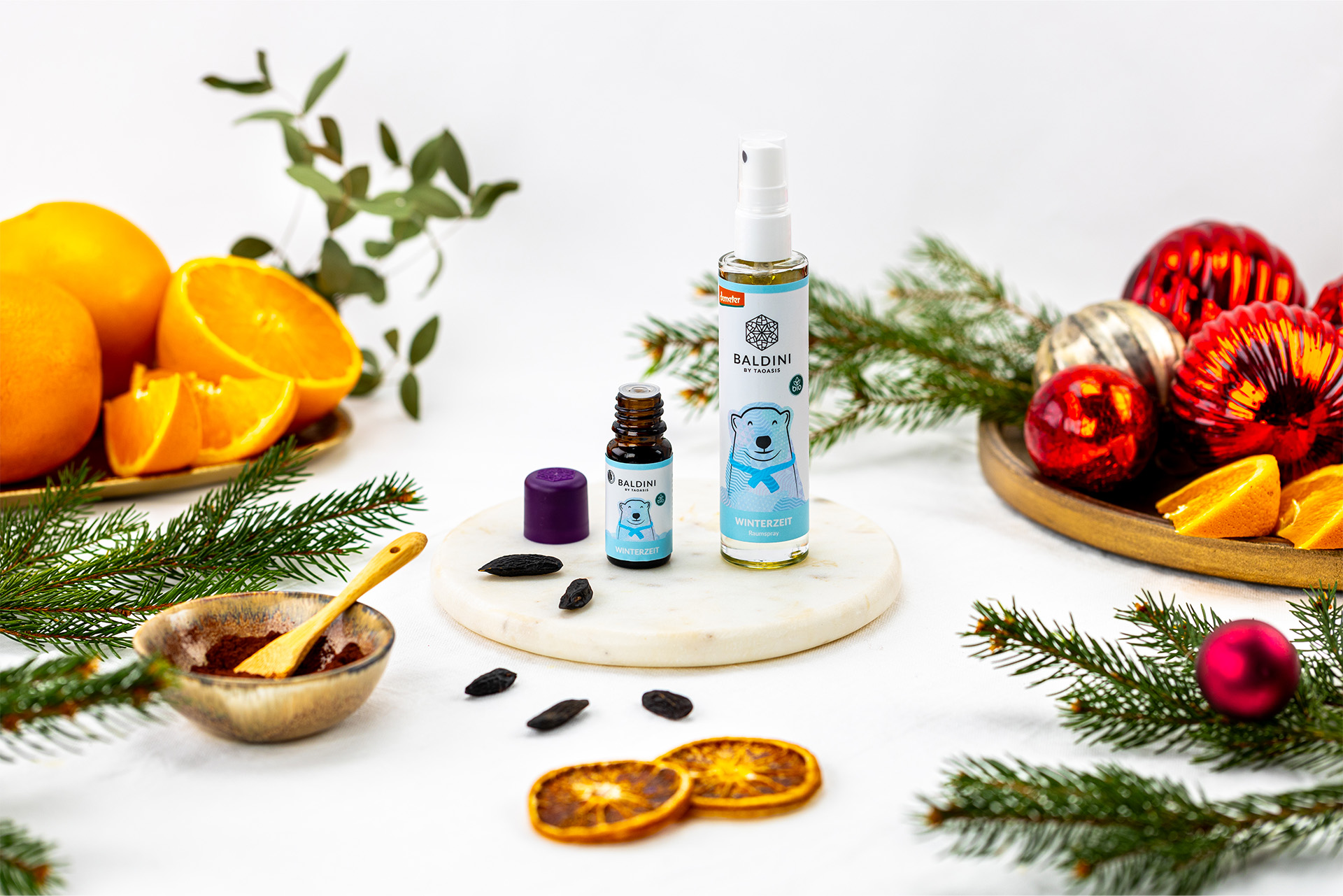 Winterzeitserie mit Raumspray und Duftkomposition. Winterliche Deko mit Obst und roten Kugeln.
