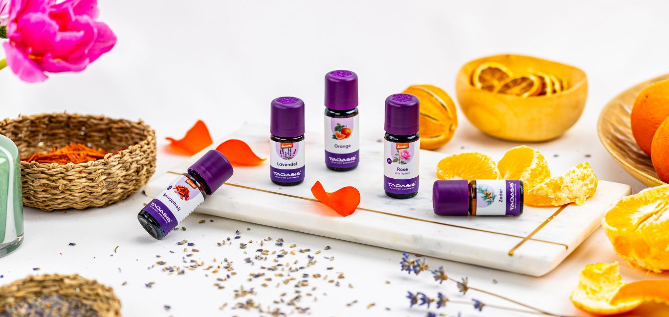 Ätherische öle auf einem Stimmungsbild, mit Orangen und Blume. Zusehen sind sandelholz, Lavendel, Orange, Rose und Zeder.