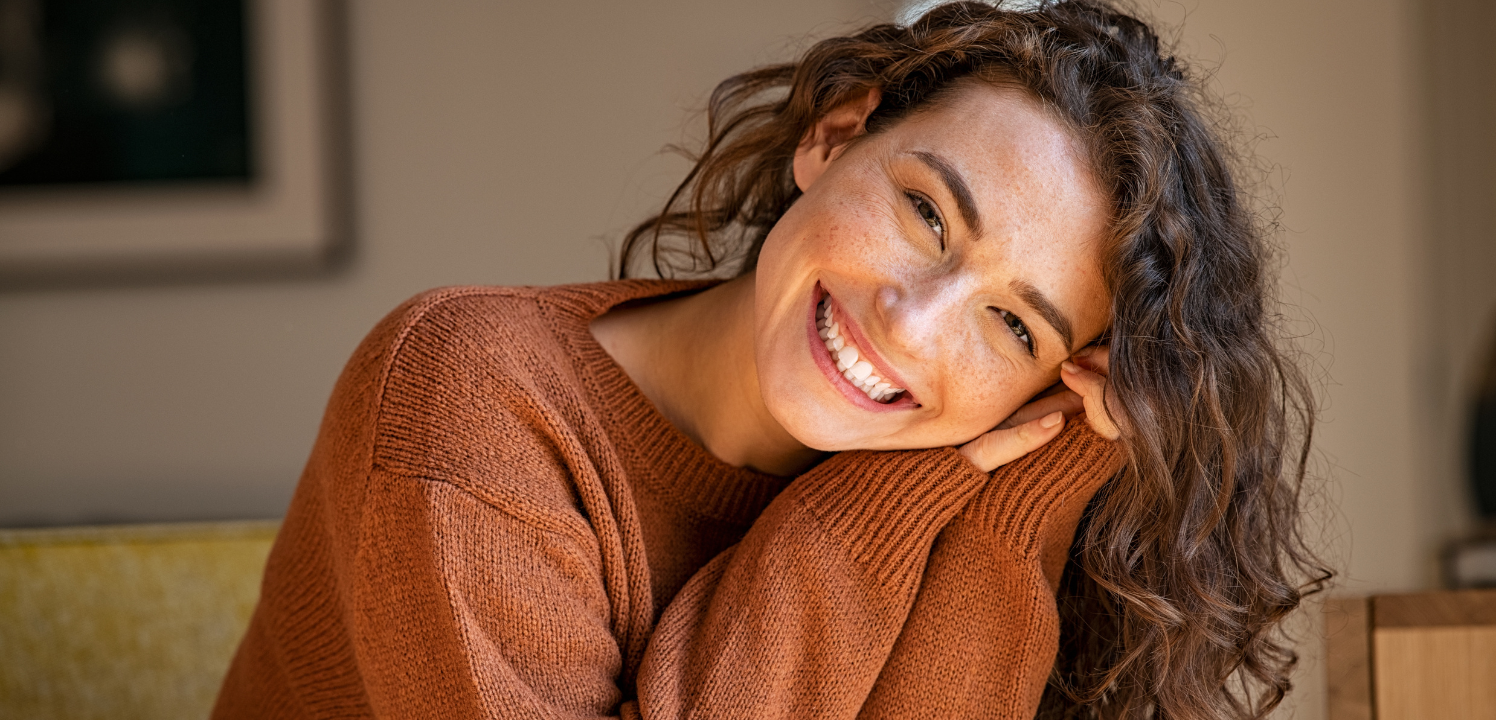Lächelnde Frau mit langen braunen Haaren und Sommersprossen