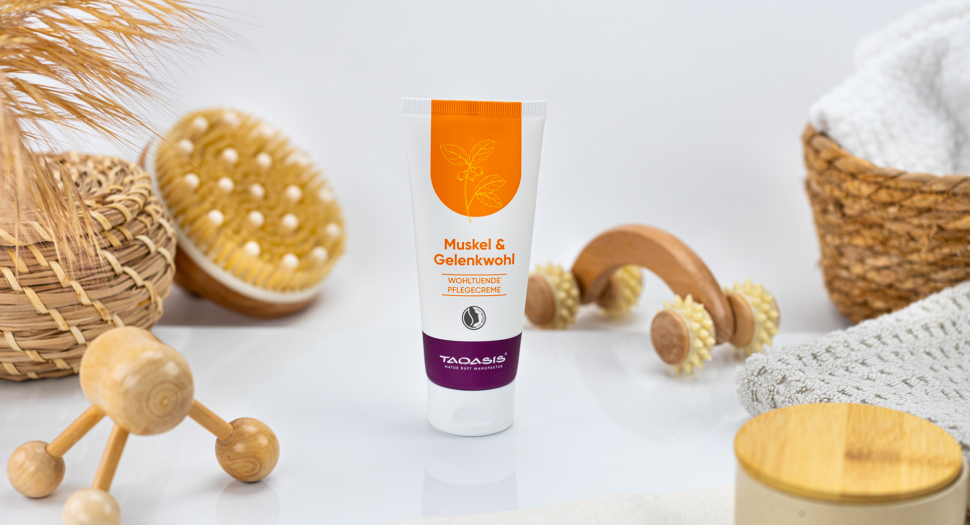 TAOASIS Muskel & Gelenkwohl Pflegecreme auf Ablage, gehalten von einer Hand in warmer Umgebung.
