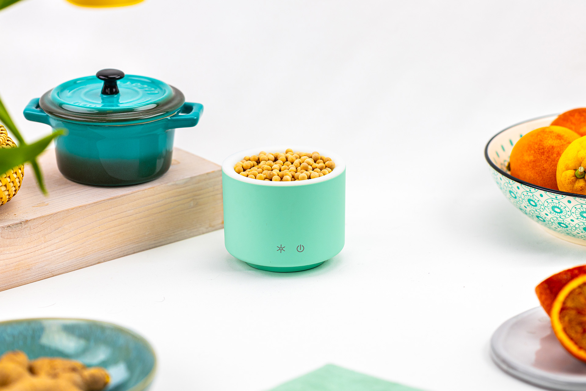 AromaStream Wood Mini mint auf weißem Hintergrund, dekoriert mit Schalen, Zitrusfrüchten und kleinem Topf.