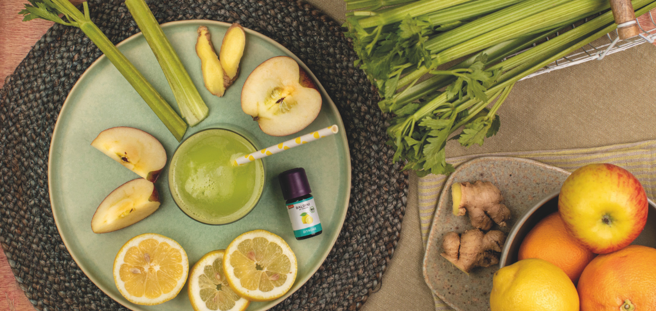 Grüner Smoothie mit Apfel, Zitrone, Sellerie und Ingwer auf einem Teller arrangiert.