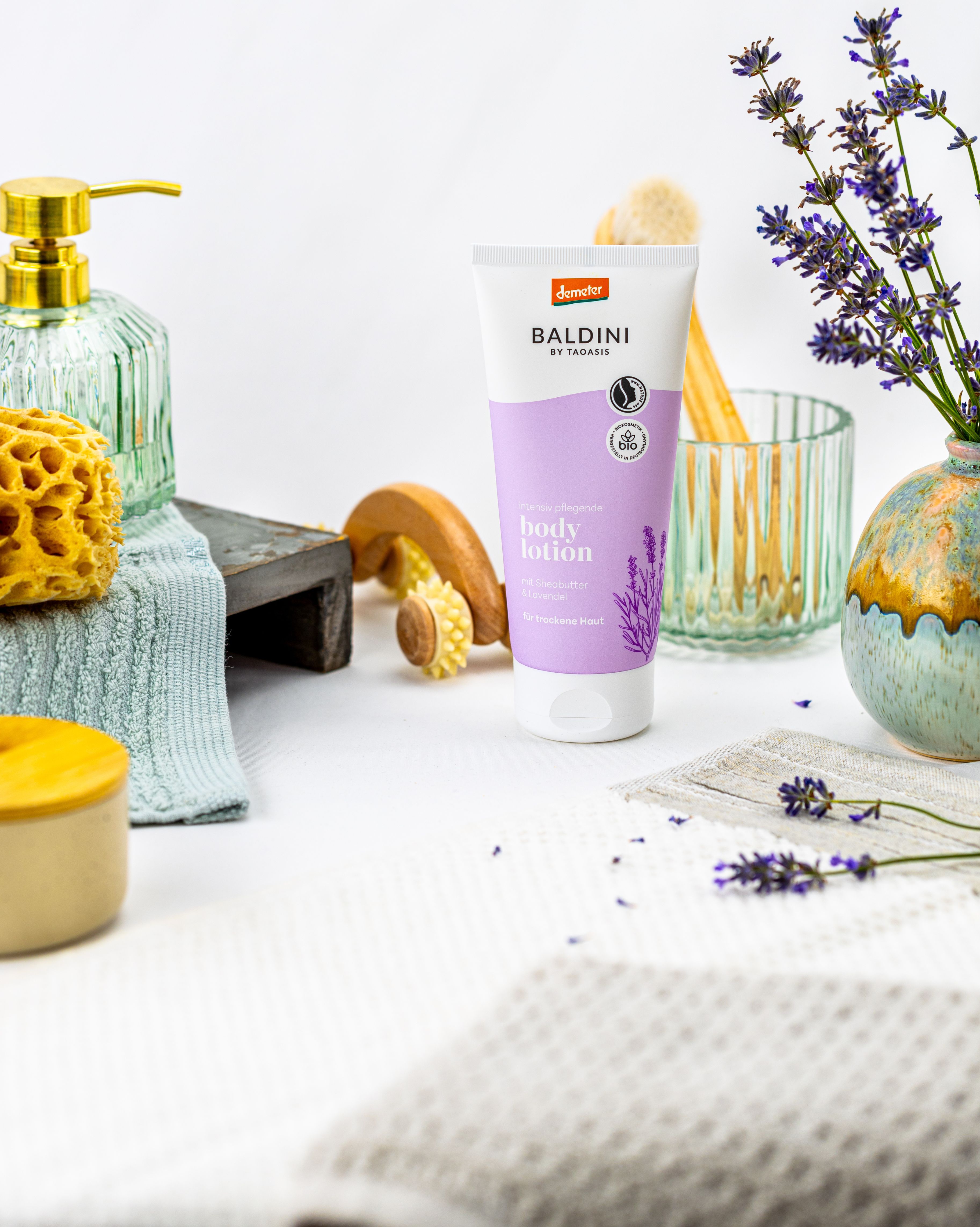 Baldini Bodylotion mit Lavendelblüten und Kosmetikutensilien.