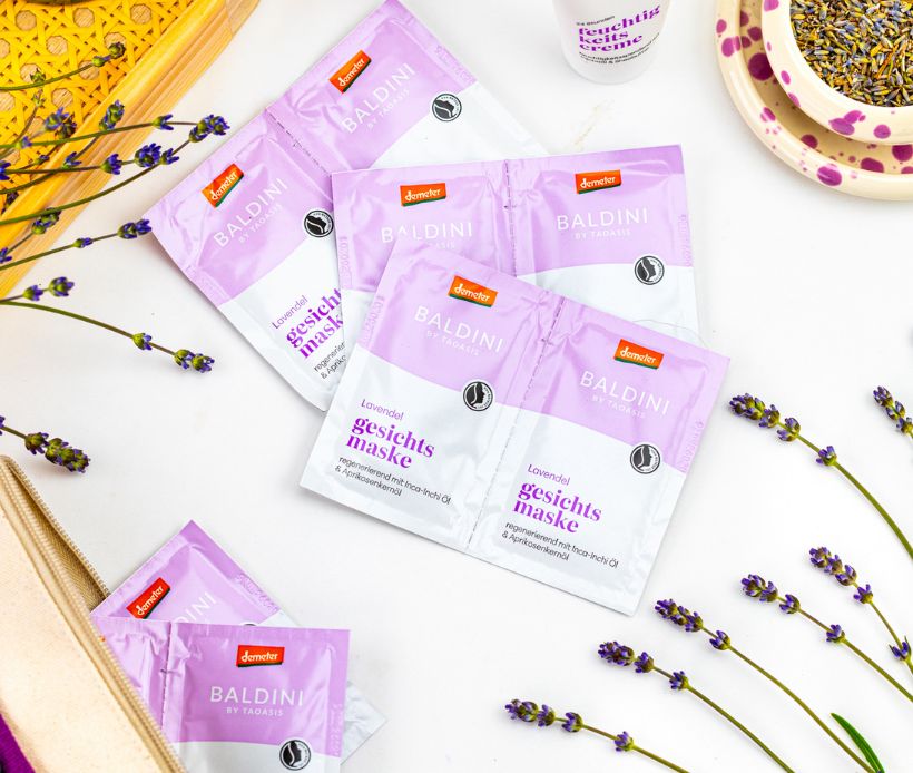 Baldini Lavendel Gesichtsmasken dekorativ mit Lavendelblüten, Körbchen und Naturaccessoires arrangiert.