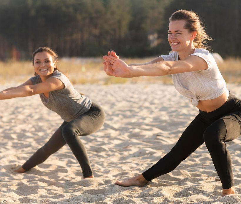 Zwei Frauen machen amStrand Dehnübungen