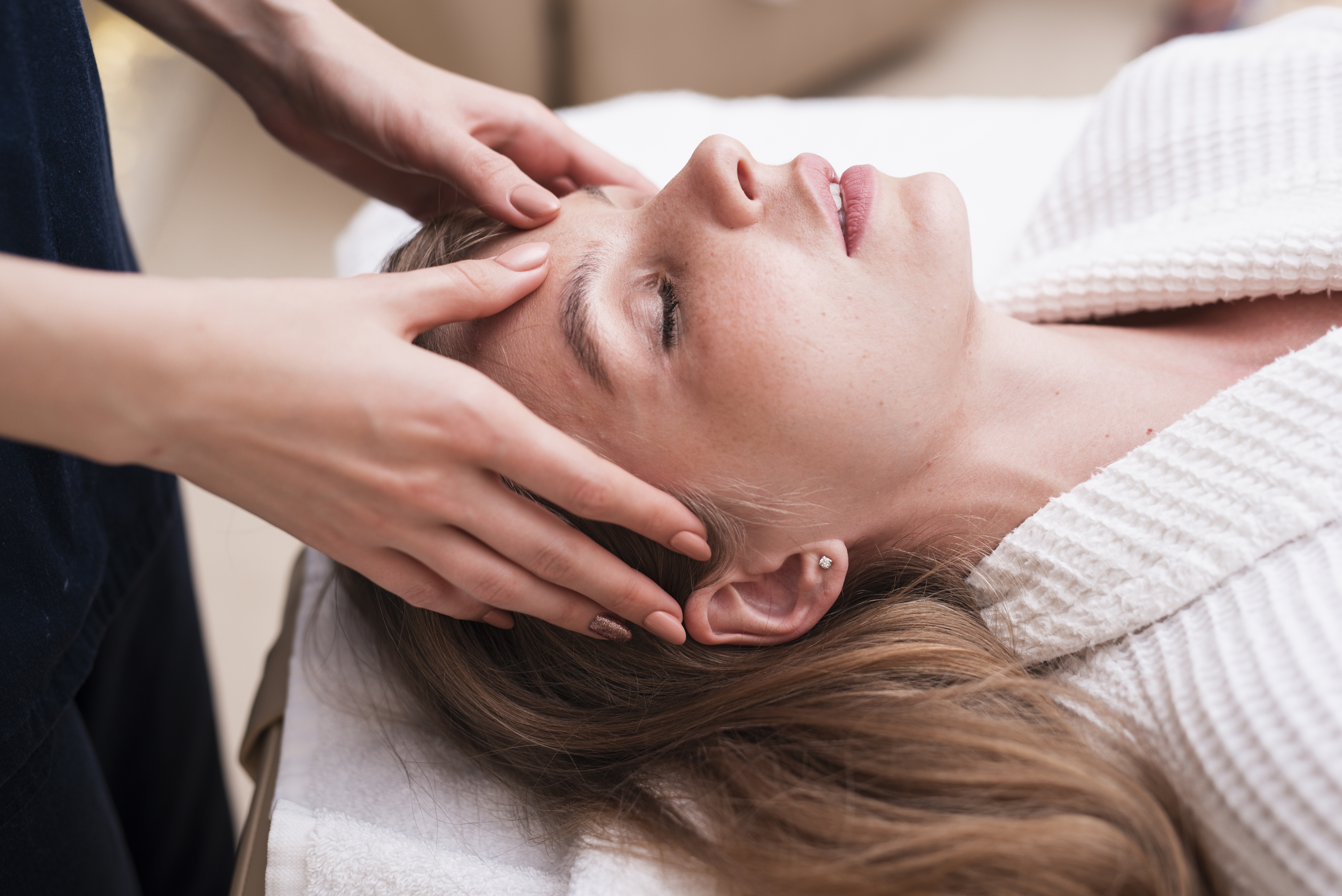 Frau liegt entspannt bei einer Kopfmassage in einer ruhigen Spa-Behandlung.