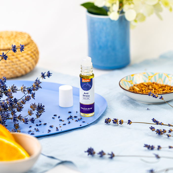 Anti-Stress Roll-on mit Lavendel in ruhiger, natürlicher Umgebung – umgeben von Blüten und warmen, entspannenden Details.