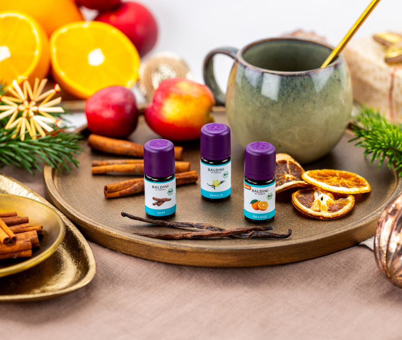 Baldini Bio-Essenzen Zimt, Vanille und Orange mit Gewürzen, Früchten und Tasse arrangiert.
