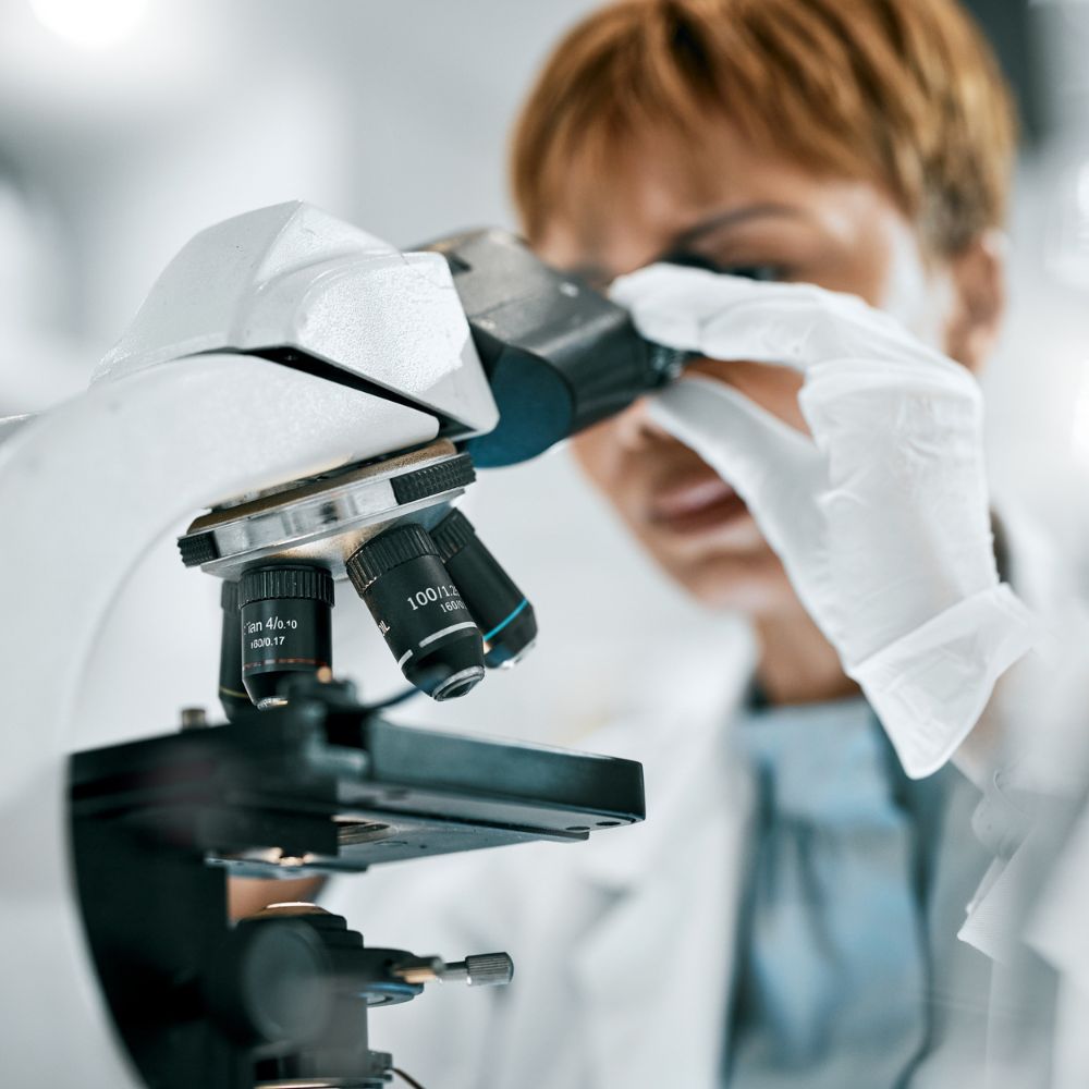 Forscherin schaut in Mikroskop.