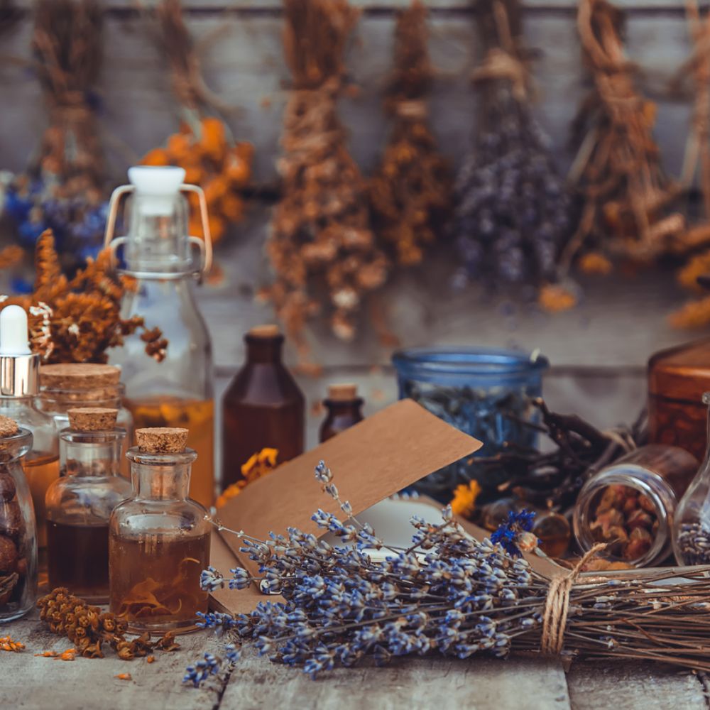 Stillleben mit Lavendel, getrockneten Kräutern und Glasfläschchen mit ätherischen Ölen auf einem rustikalen Holztisch – natürliche Aromatherapie und Duftöle.