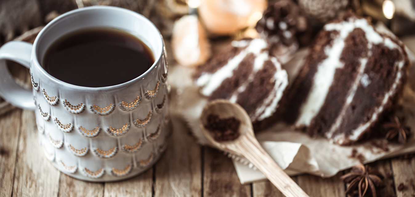 Tasse mit heißer Schokolade neben einem Stück Schokoladenkuchen.