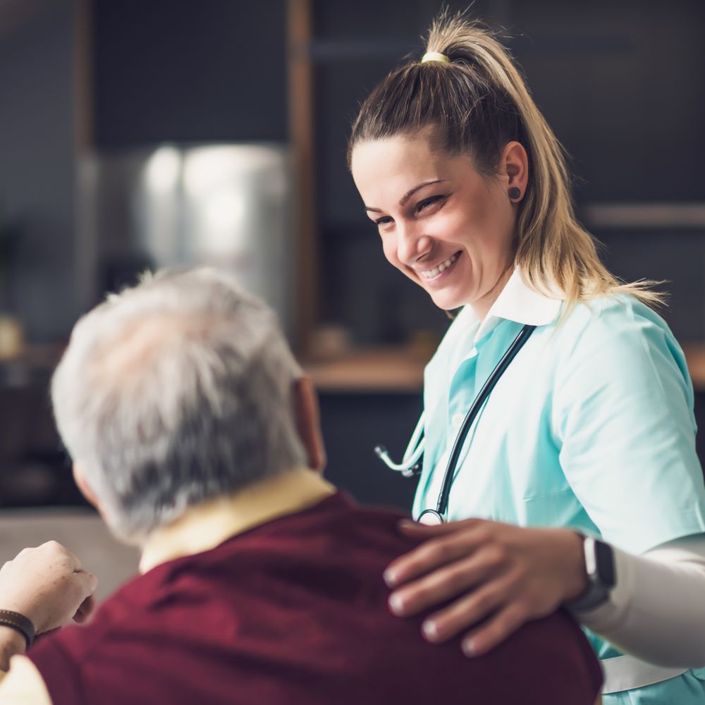 Ärztin, die einem Mann die Hand auf die Schulter legt.