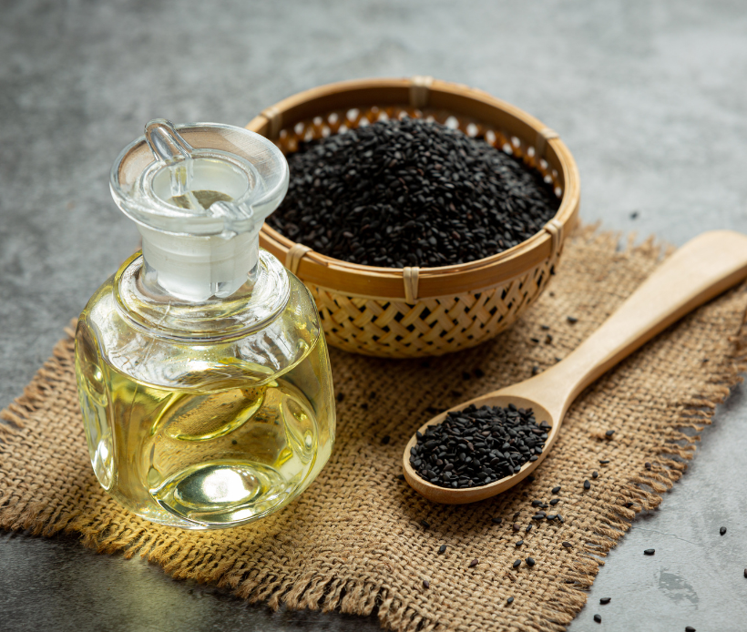 Schlafkümmelöl im Glas mit Löffel und Schwarzkümmelsamen mit einer Schale