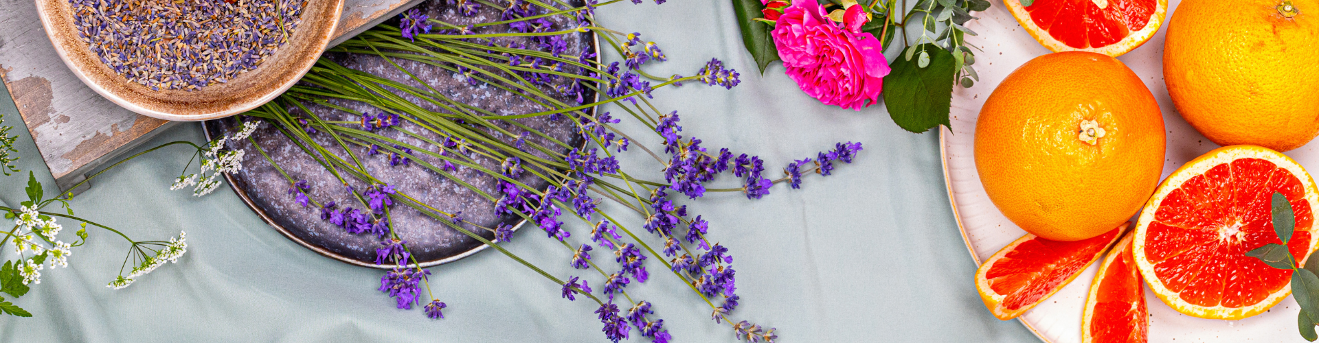 Frische Lavendelzweige, leuchtende Rosenblüten und saftige Grapefruit auf Meersalz arrangiert.