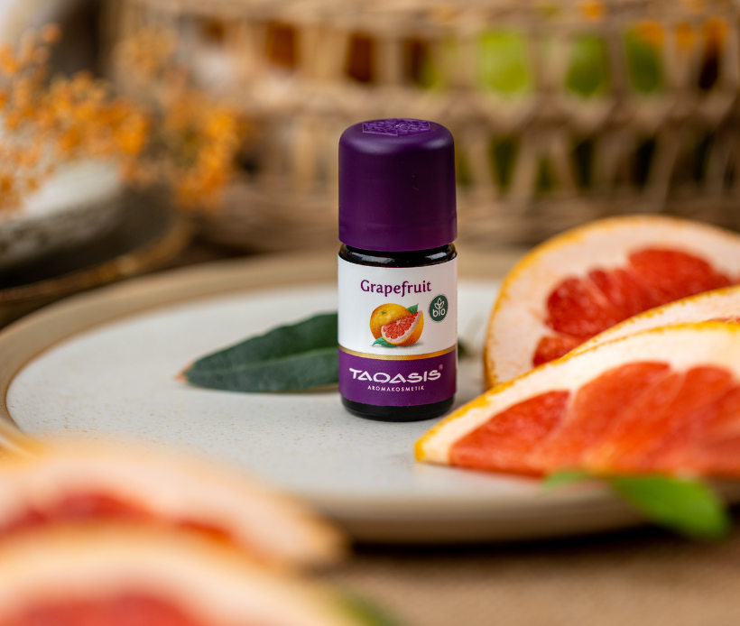 TAOASIS ätherisches Grapefruitöl mit aufgeschnittener Grapefruit in natürlicher Aromatherapie-Szene.