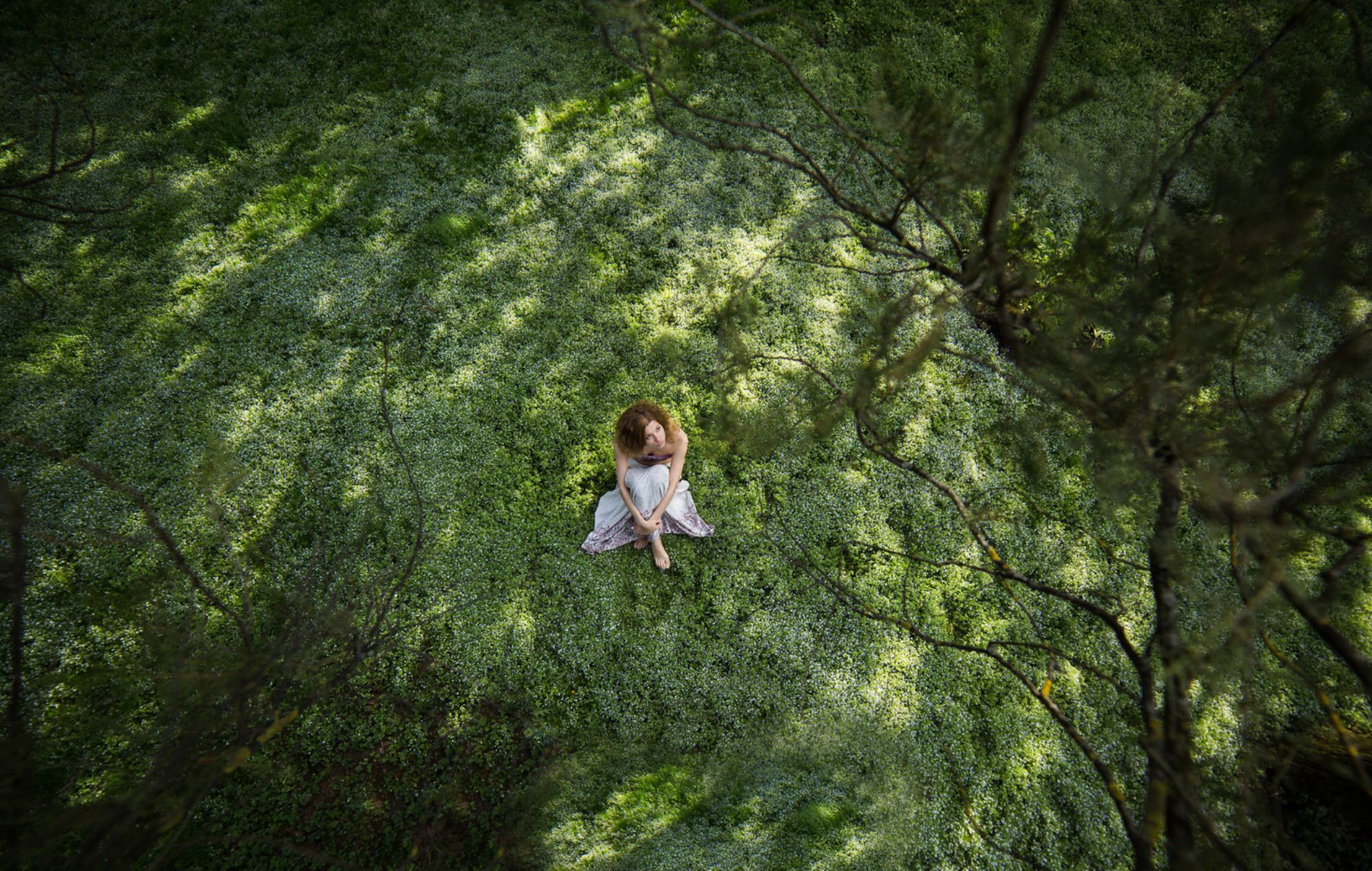 Frau sitzt im Wald auf dem Boden 