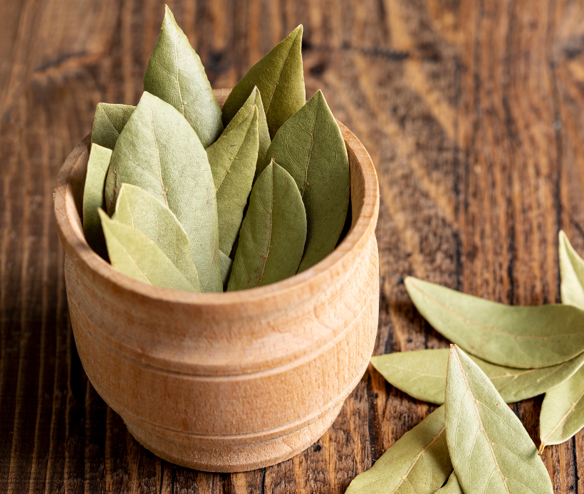 Getrocknete Salbeiblätter in einer kleinen Holzschale auf rustikalem Holztisch.