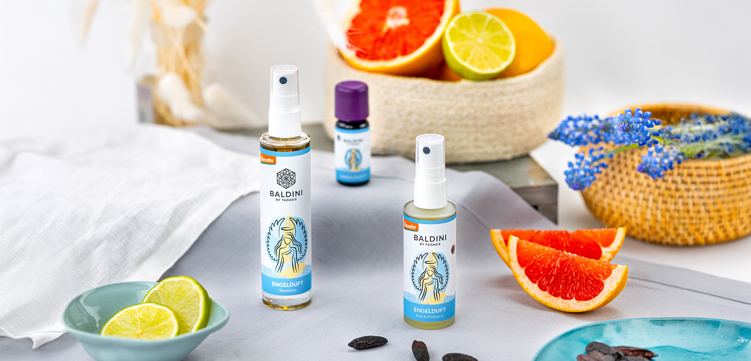Baldini Engelduft Raumspray und Aura & Bodyspray mit ätherischem Öl, Zitrusfrüchten und blauen Blüten dekorativ arrangiert.