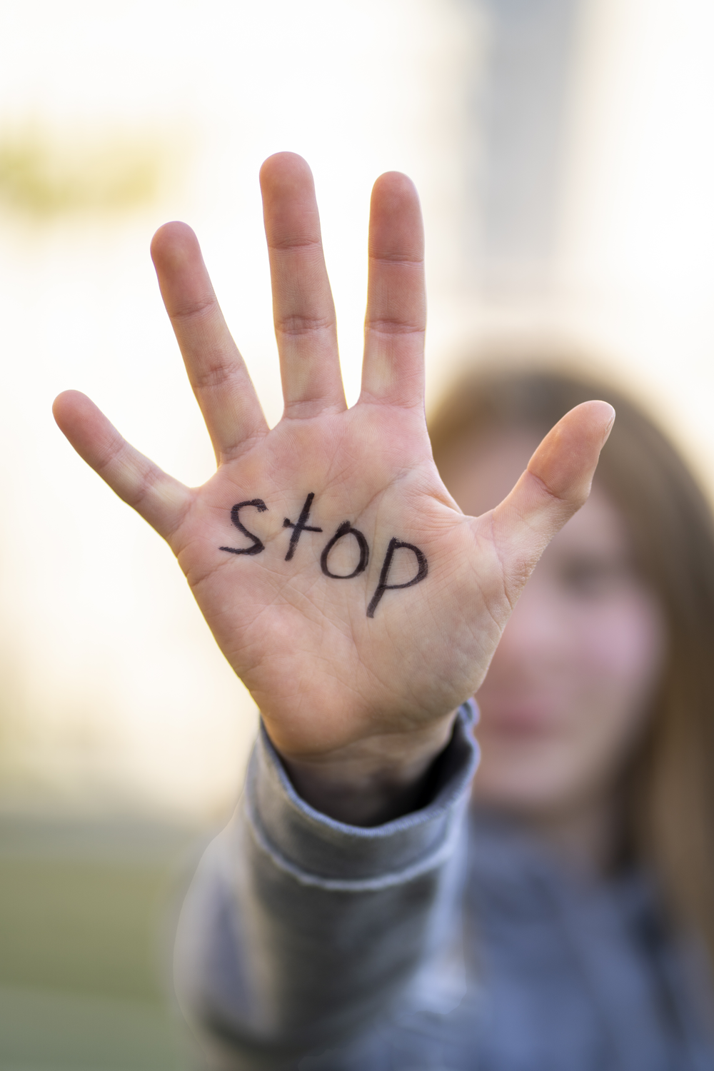 Mensch zeugt Handfläche wo "STOP" drauf steht 