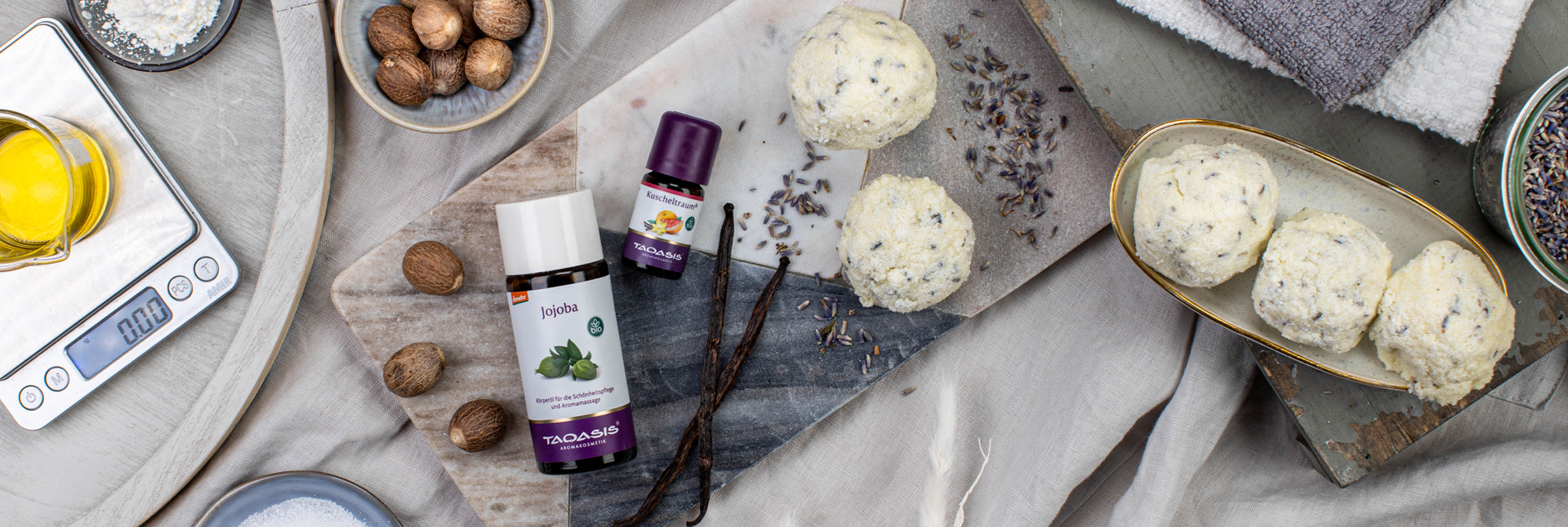 DIY-Badekugeln mit Jojobaöl, Lavendel und Vanille, dekorativ arrangiert auf Steinplatte mit Zutaten und Utensilien